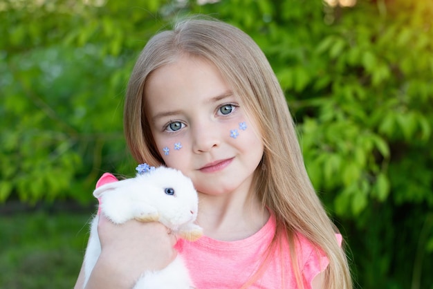 una niña sostiene un pequeño conejo blanco en sus brazos Símbolo del nuevo año 2023