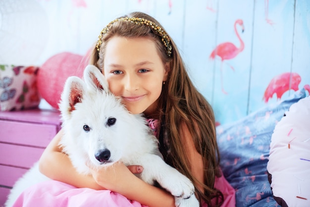 Foto niña sostiene un perro en la habitación. el concepto de amistad y estilo de vida.