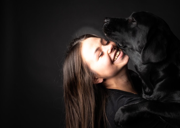 Una niña sostiene un perro Labrador Retriever en sus brazos.