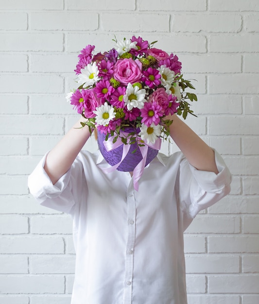 La niña sostiene un ramo de flores y cubre su rostro. concepto de impersonalidad y anonimato.