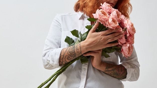 La niña sostiene un ramo de rosas rosadas.