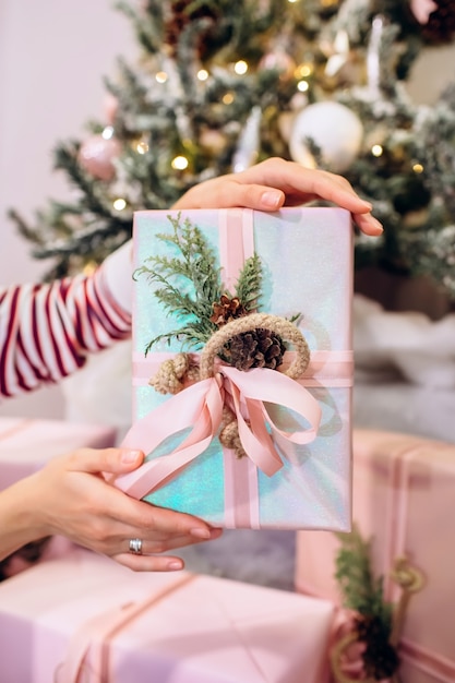 Niña sostiene un regalo, árbol de Navidad, caja rosa con un regalo