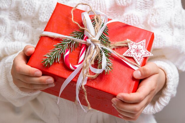 La niña sostiene un regalo de Navidad envuelto en papel de regalo rojo.