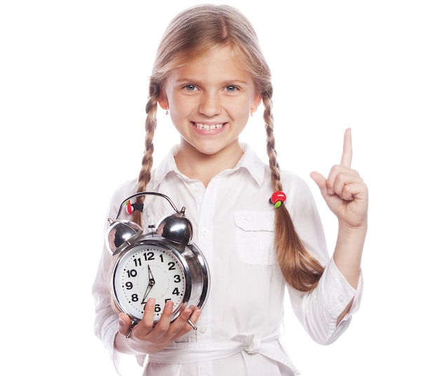 Foto la niña sostiene el reloj mientras apunta hacia arriba con el dedo índice aislado sobre el fondo blanco