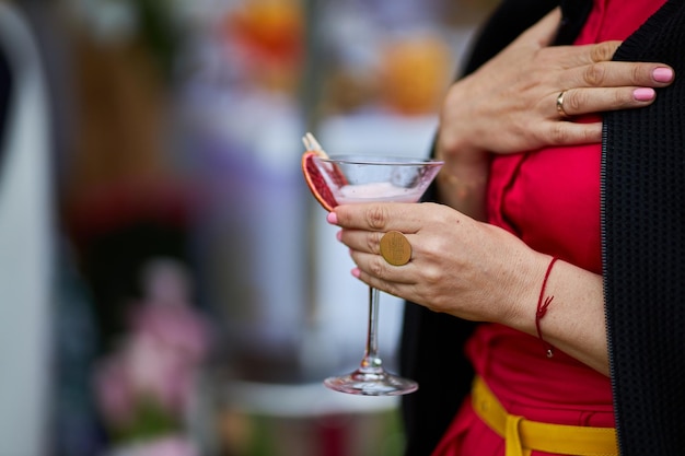 la niña sostiene en su mano una copa de martini con una rodaja de naranja seca cerrada