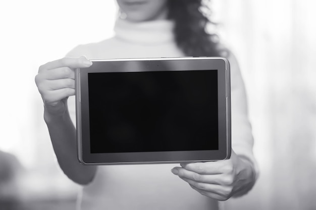 La niña sostiene la tableta. La niña tiene una computadora con una pantalla en sus manos. Las manos sostienen la pantalla con un espacio vacío.