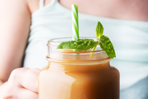 Una niña sostiene una taza de vidrio con jugo en la mano.