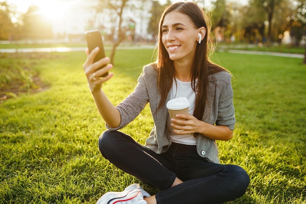 La niña sostiene el teléfono y el café en la mano Sunset Summertime