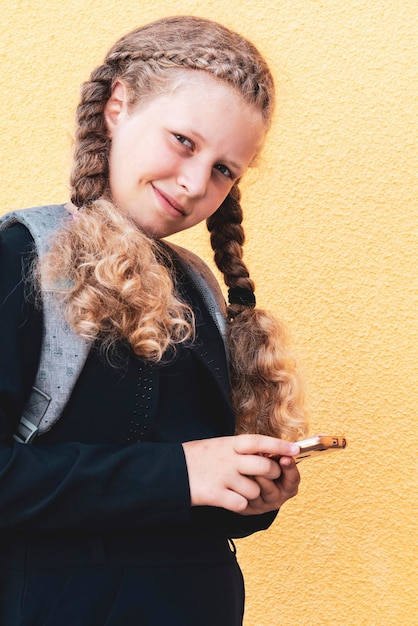 Foto niña sostiene un teléfono inteligente concepto de uso de aparatos por parte de los niños problema usando tabletas y aparatos niña en un espacio de copia uniforme