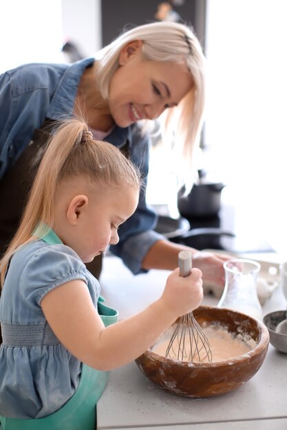 Niña y su abuela preparando masa juntos en la cocina