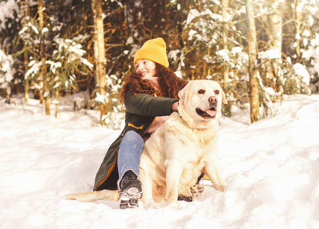 Niña con su amado perro Labrador en un parque de invierno