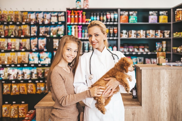 Niña con su cachorro caniche en veterinaria.