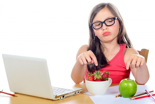 Una niña en su escritorio mirando su merienda