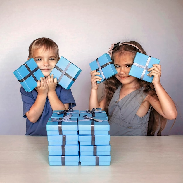 Niña con su hermano menor cerca de una enorme pila de cajas de regalo