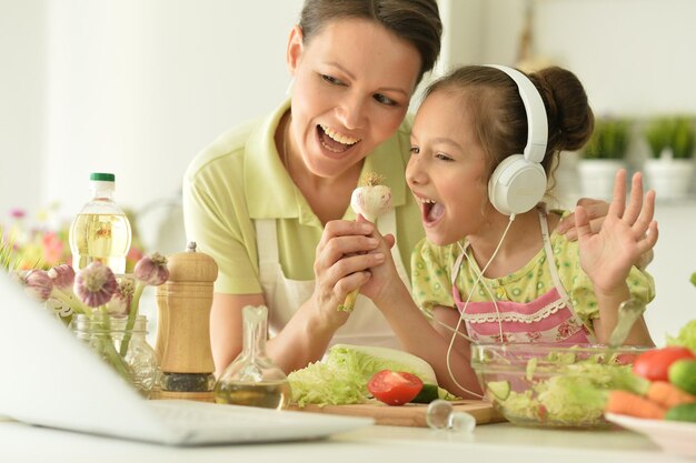 Niña con su madre cocinando juntos en la mesa de la cocina