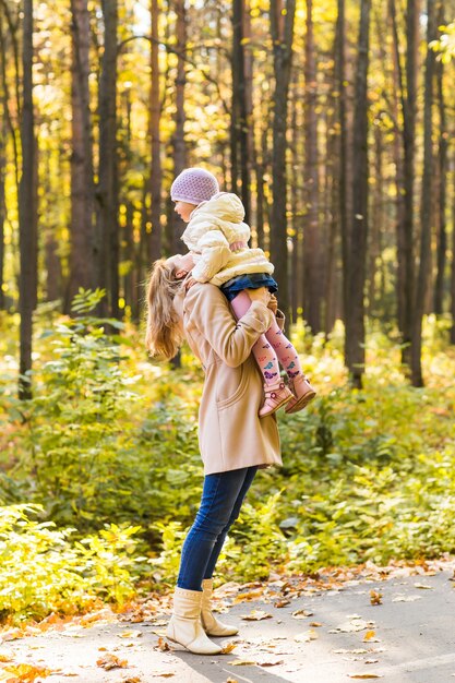 Niña y su madre jugando en el parque de otoño.