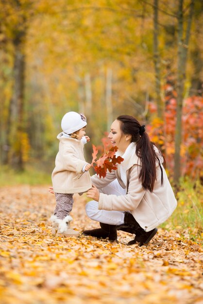 Niña y su madre jugando en el parque de otoño.