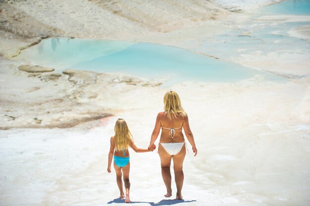 Una niña y su madre en traje de baño caminan por la Montaña Blanca en la ciudad de Pamukkale. pavo