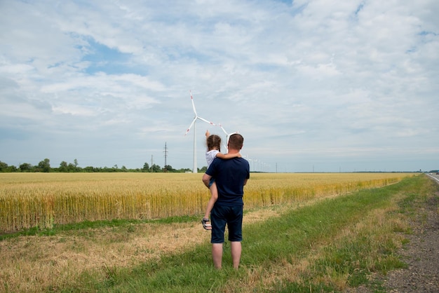 Una niña y su papá miran el generador de viento en el campo Ecología Futuro