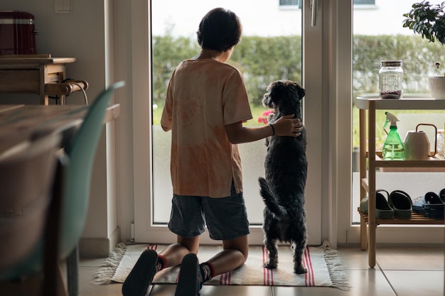 Niña con su pequeño perro negro mirando hacia el jardín