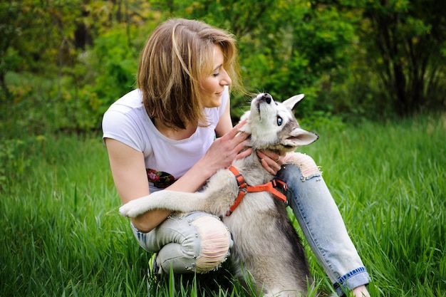 Una niña y su perro husky caminando en un parque