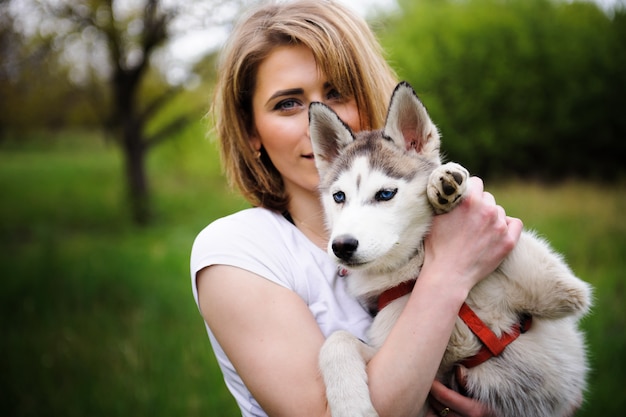 Una niña y su perro husky caminando en un parque