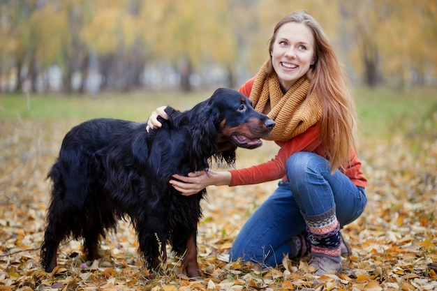 Niña y su perro setter gordon en el parque otoño