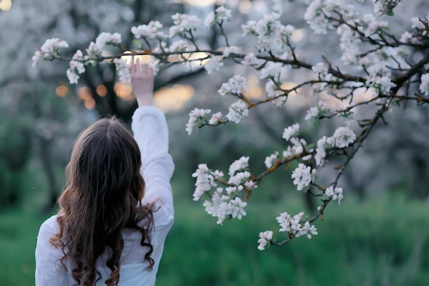 niña sueña vista posterior, retrato de primavera niña feliz en un jardín floreciente, abril estacional