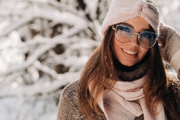 Una niña con un suéter y gafas en invierno en un bosque cubierto de nieve.