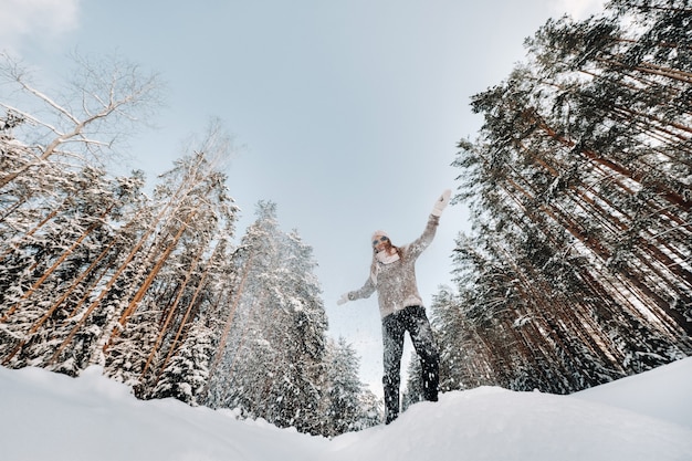 Una niña con un suéter y guantes en invierno se encuentra sobre un fondo cubierto de nieve