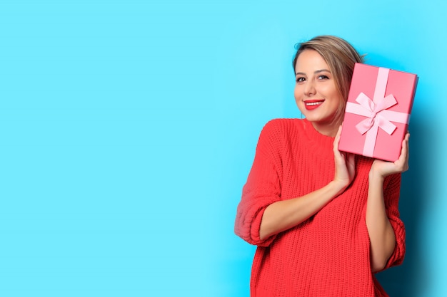 niña de suéter rojo con caja de regalo