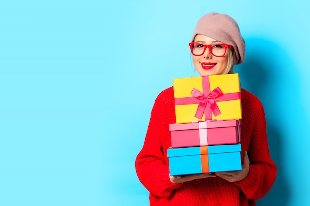 Niña en suéter rojo con cajas de regalo