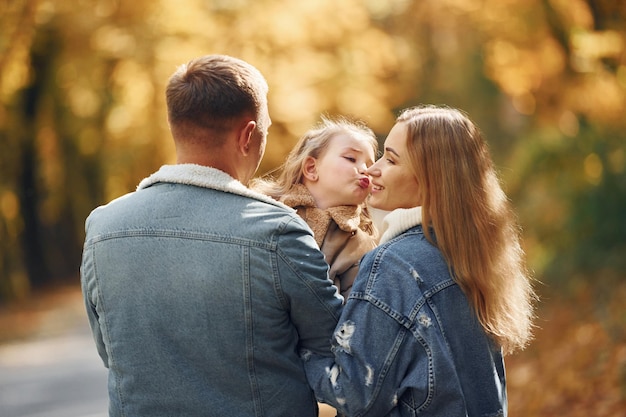 Niña con sus padres Familia feliz está en el parque en otoño juntos