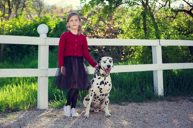 Niña con sus perros dálmatas en un parque de primavera.