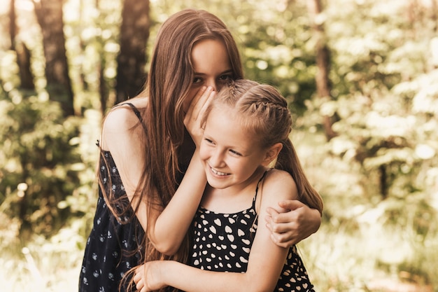 Una niña susurra un secreto al oído de su hermana.