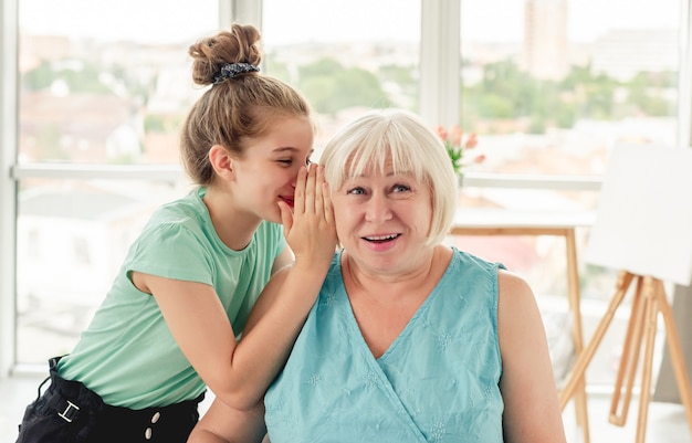 Niña susurrando un secreto a la abuela