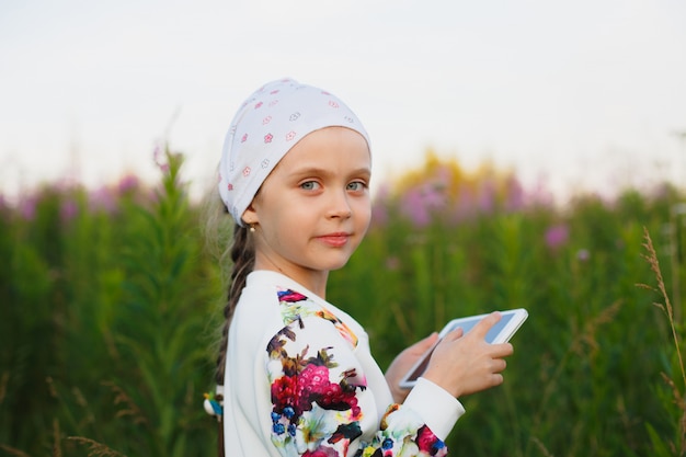 Niña con tableta digital en la naturaleza