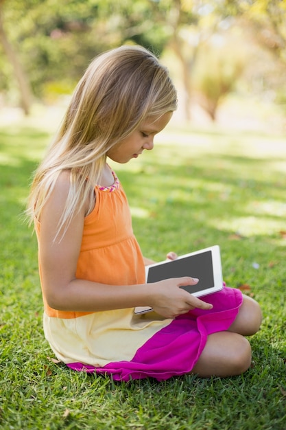 Niña con tableta digital en el parque