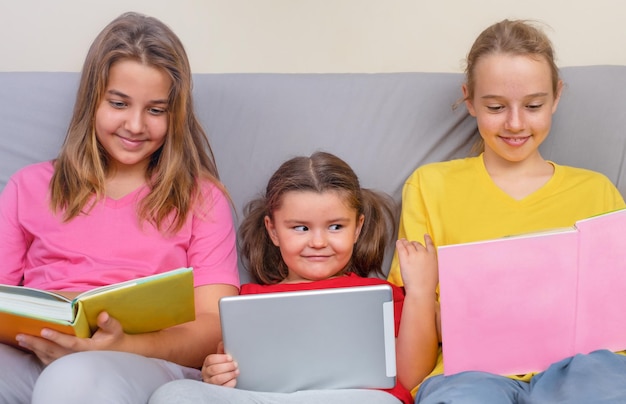 Una niña con una tableta mira los libros a un adolescente en el sofá