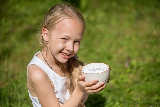 Niña con taza de leche en la naturaleza