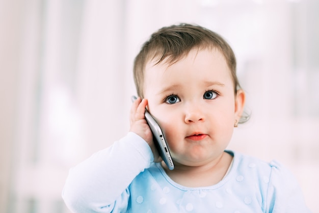 Una niña con un teléfono inteligente en sus manos se sienta y presiona muy dulce