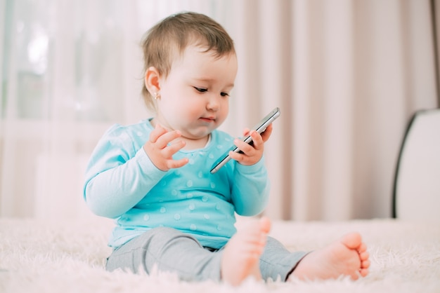 Una niña con un teléfono inteligente en sus manos se sienta y presiona