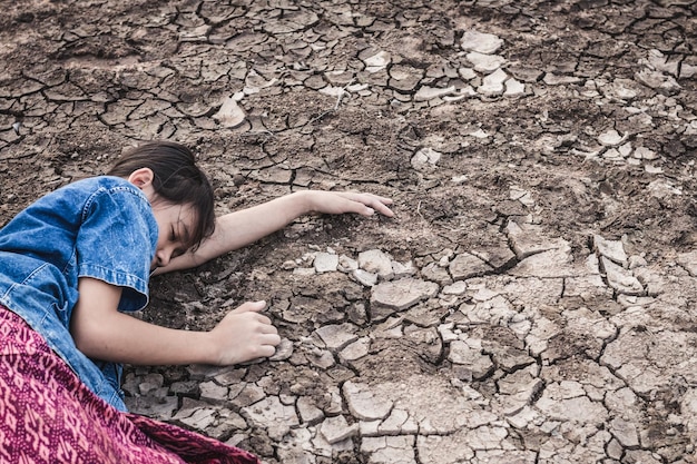 Foto niña tendida en la tierra seca