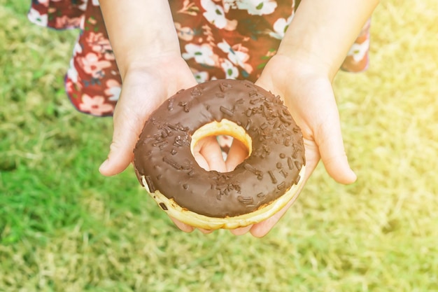 niña, tenencia, un, donut de chocolate, posición, en, el, césped