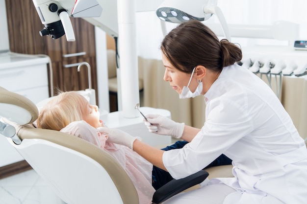 Niña teniendo sus dientes revisados por una doctora en la clínica