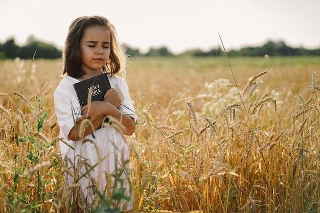 La niña tiene la Biblia en sus manos. Leyendo la Santa Biblia en un campo. Concepto de fe, espiritualidad y religión. Paz, esperanza