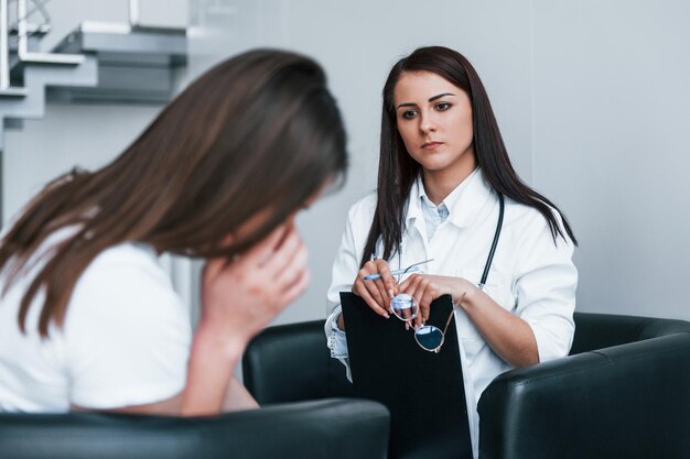 Niña tiene crisis mental y llanto Mujer joven tiene una visita a una doctora en una clínica moderna