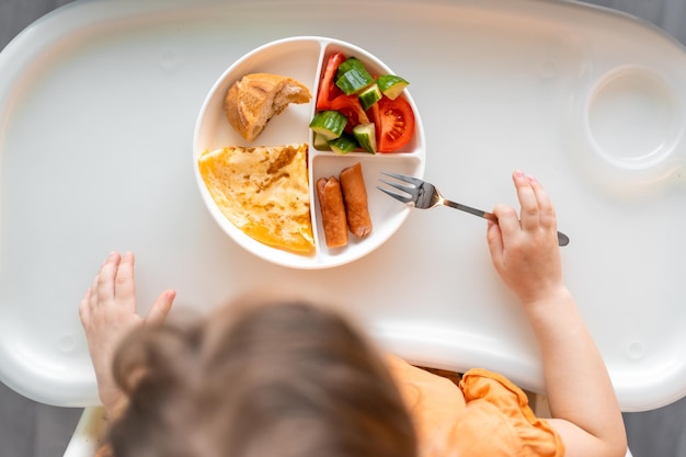 La niña tiene un desayuno equilibrado en la cocina de casa por la mañana