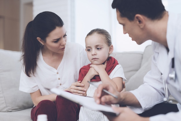 La niña tiene dolor de garganta y mamá se coge las manos.