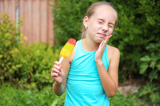 La niña tiene dolor de muelas por helado frío.